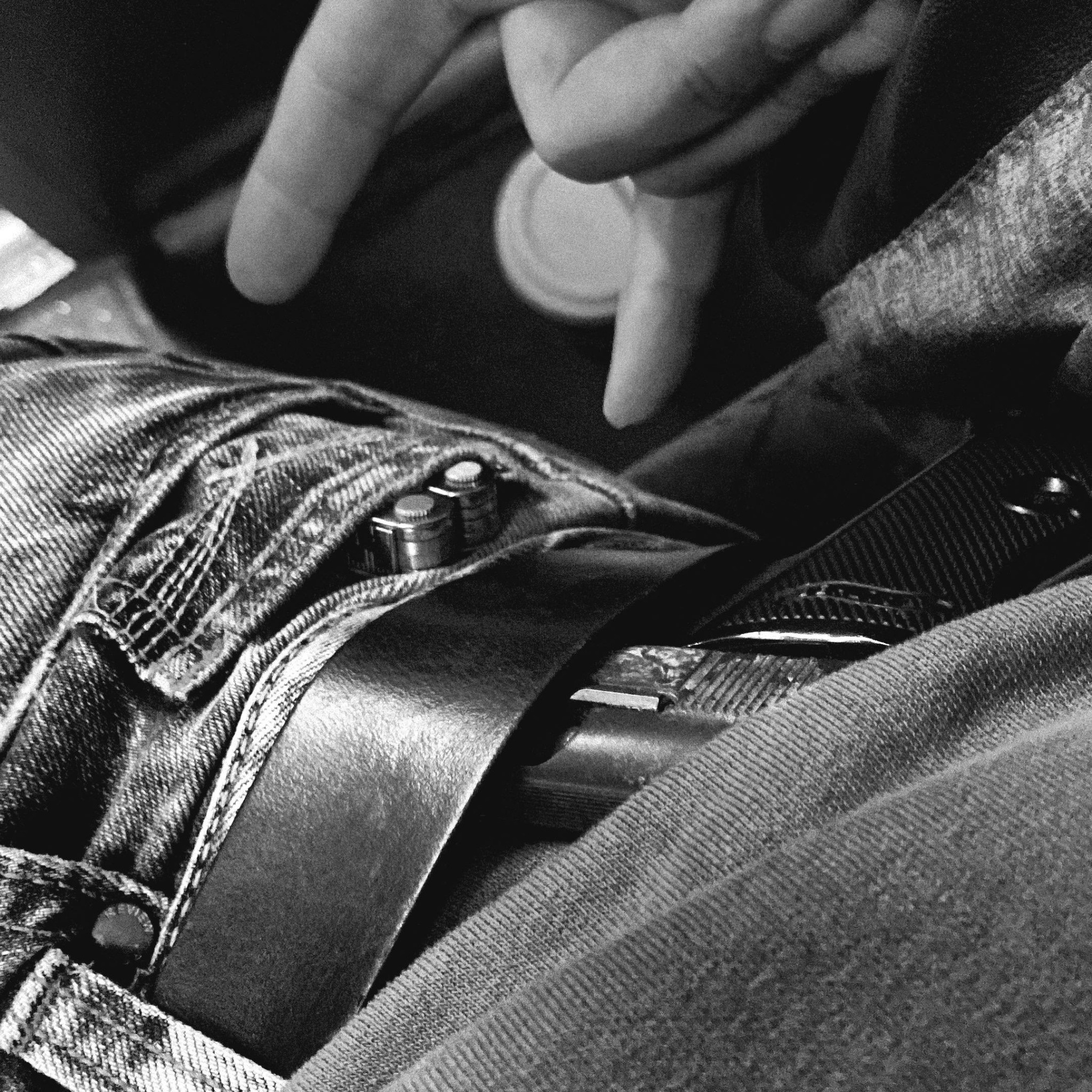 Close detail of a hand, belt and dark clothing