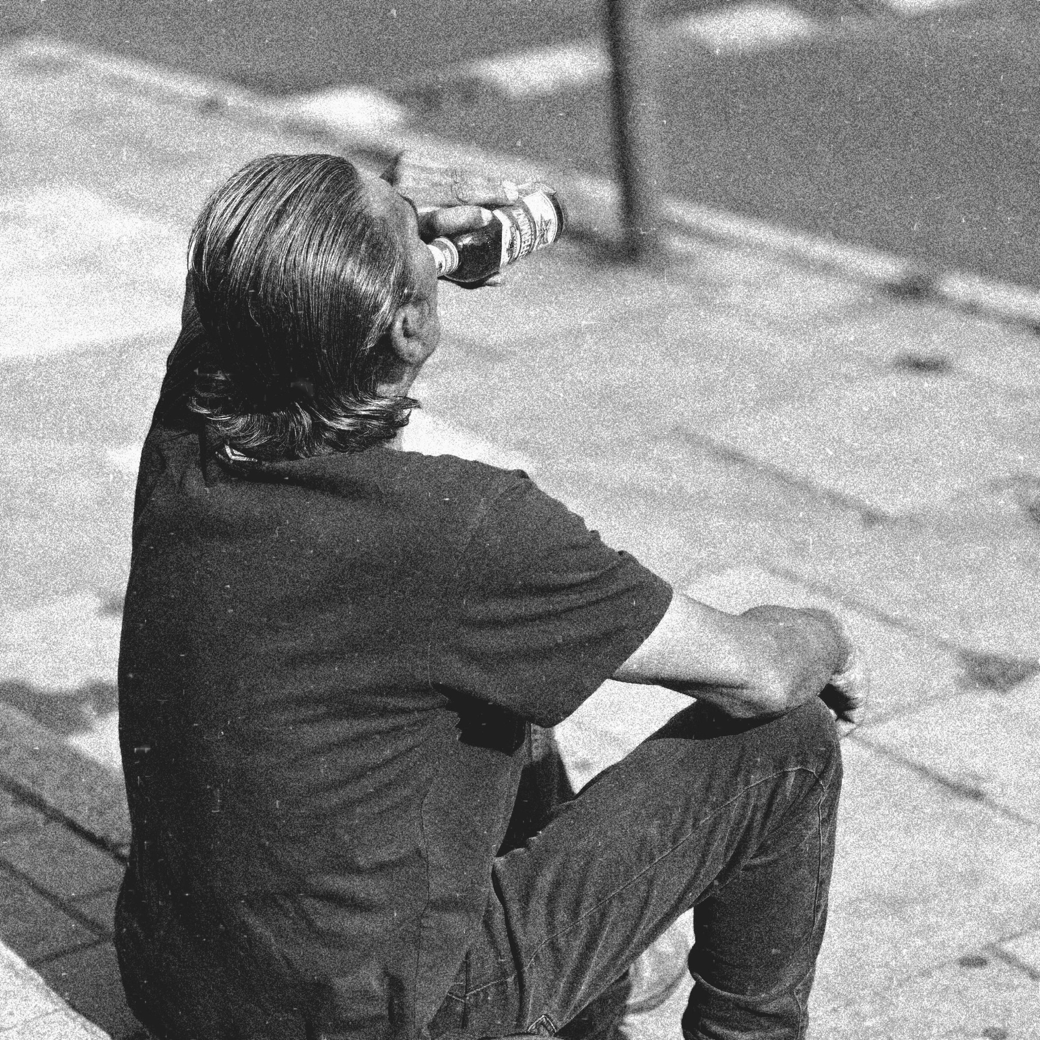 Solitary seated figure drinking in an urban space